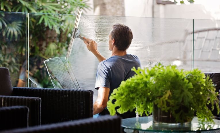Man cleaning a glass window with a squeegee at home