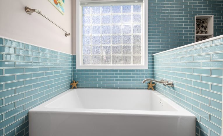 Bathroom with tiled wall and bathtub showing sealant lines