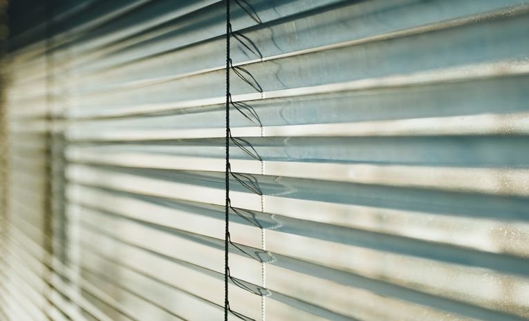 White metal venetian blinds with sunlight patterns